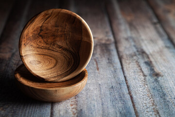 Close-up of wooden bowls stacked on top of one another, placed over a wooden background.