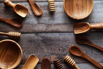 A top-down view of various types of wooden ladles and bowls placed on a wooden background.