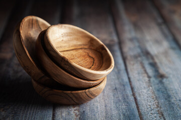 Close-up of wooden bowls, placed over a wooden background.