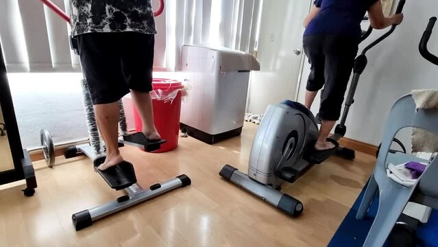 Elderly physiotherapy patients performing steppers exercise to strengthen weakened leg muscles as recovery therapy