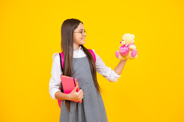 Back to school. Teenager schoolgirl hold book with toy ready to learn. School children on isolated yellow studio background.