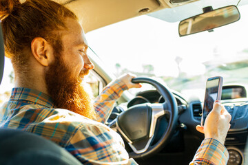 handsome redhaired ginger man with long beard going on trip during summer vacation on new car