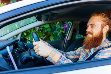 handsome redhaired ginger man with long beard going on trip during summer vacation on new car