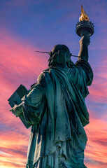 Fototapeta premium Great back photo of the Statue of Liberty in New York (USA) and the Big Apple at dawn, symbol of the city of Manhattan and democracy in the world.