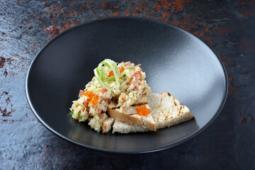 Cooked meat tartare with red caviar and croutons in a beautiful plate.