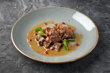 Sliced beef stew with mint leaves and cranberries in a beautiful plate.