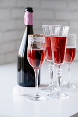glasses of rose champagne on white table, white brick wall background