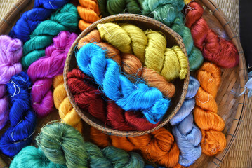 Tie of colorful and shiny beautiful silk yarn dyed placed in a pile of round bamboo baskets....