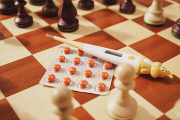 Packaging of medical pills and a children's thermometer with chess pieces on a chessboard