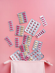 Flat lay composition with pink female toiletry bag blisters on color background