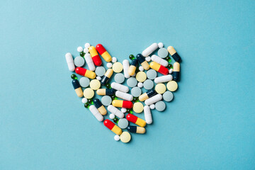 heart shape made of different pills on blue background