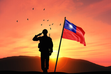 Silhouette of a soldier with the Taiwan flag stands against the background of a sunset or sunrise....