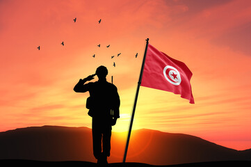 Silhouette of a soldier with the Tunisia flag stands against the background of a sunset or sunrise. Concept of national holidays. Commemoration Day.