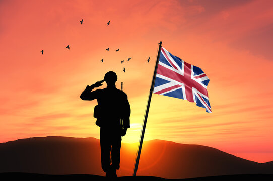 Silhouette of a soldier with the United Kingdom flag stands against the background of a sunset or sunrise. Concept of national holidays. Commemoration Day.