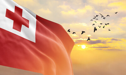 Waving flag of Tonga against the background of a sunset or sunrise. Tonga flag for Independence...