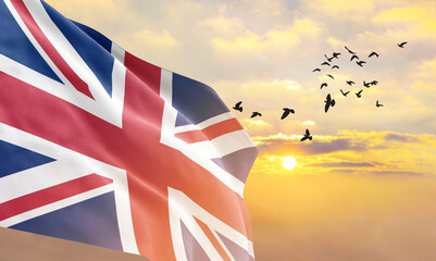 Waving flag of United Kingdom against the background of a sunset or sunrise. United Kingdom flag...