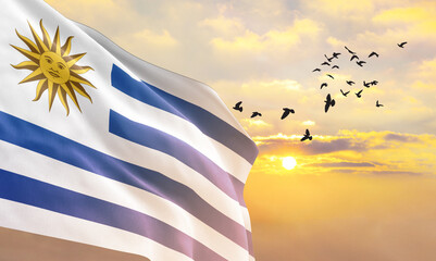 Waving flag of Uruguay against the background of a sunset or sunrise. Uruguay flag for Independence...