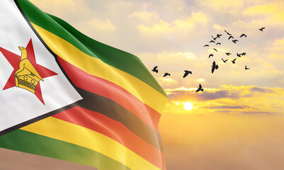 Waving flag of Zimbabwe against the background of a sunset or sunrise. Zimbabwe flag for Independence Day. The symbol of the state on wavy fabric. - obrazy, fototapety, plakaty