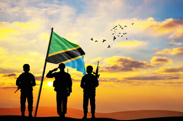 Silhouettes of soldiers with the Tanzania flag stand against the background of a sunset or sunrise. Concept of national holidays. Commemoration Day.