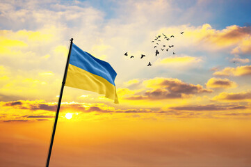 Waving flag of Ukraine against the background of a sunset or sunrise. Ukraine flag for Independence Day. The symbol of the state on wavy fabric.