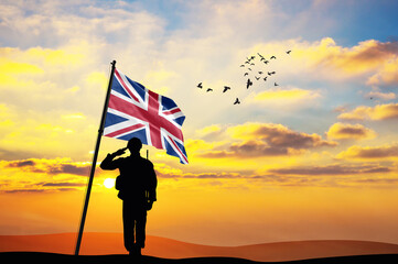 Silhouette of a soldier with the United Kingdom flag stands against the background of a sunset or...