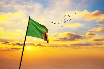 Waving flag of Zambia against the background of a sunset or sunrise. Zambia flag for Independence...