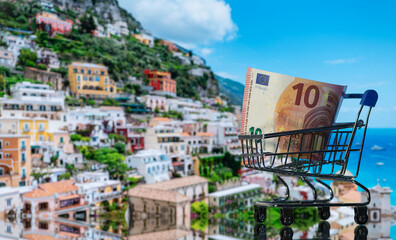 A 10 euro note in a shopping trolley with the Italian city of Positano in the background
