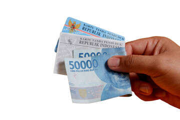 A man's hand is holding a photocopy of his KTP and a 50,000 rupiah note. concept illustration of buying or bribing election votes