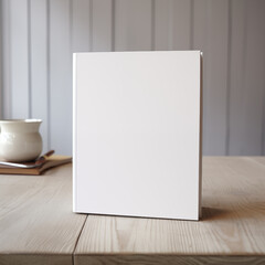 Mockup standing book with clear white cover on a wooden desk with a coffee cup and gray wooden background. Home Interior ambiance.