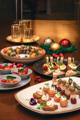 Fotografías de una cena de navidad con elementos navideños como bolas de navidad, pino y velas....