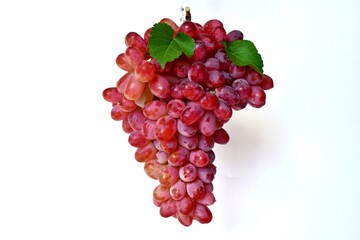 Red grape fruit with green grape leaves on white background.