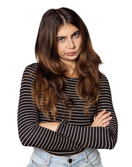 Young Caucasian woman in studio setting frowning face in displeasure, keeps arms folded.