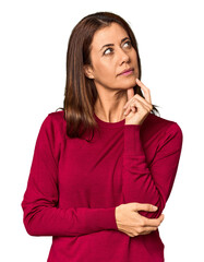 Elegant middle-aged Caucasian woman in studio setting thinking and looking up, being reflective,...