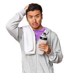 Chinese man with sportswear, towel, bottle in studio being shocked, she has remembered important...