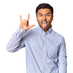 Young Chinese man in studio background showing a horns gesture as a revolution concept.