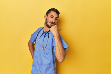 Young Hispanic male nurse Young Hispanic male nurse poses confidently points with thumb finger...