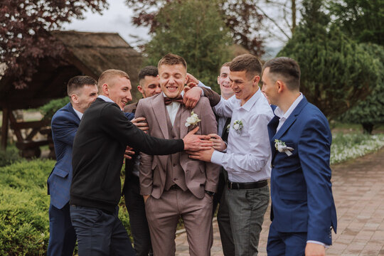 Cheerful, young, energetic witnesses of the groom next to the groom. Friends congratulate the groom. Groom and his funny friends having fun on the wedding day of the newlyweds.