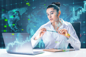 Attractive young european businesswoman using laptop at desk with growing upward chart, map, arrows...