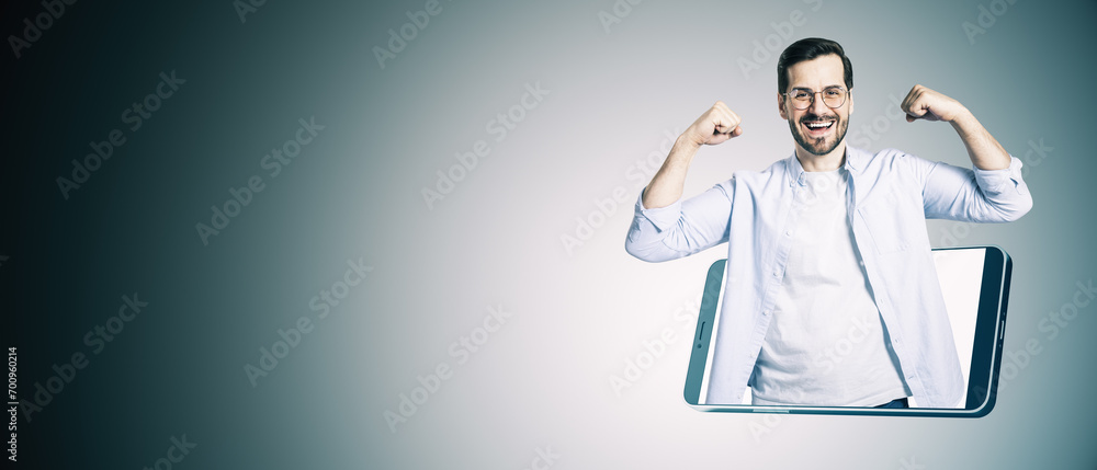 Poster happy young european businessman inside smartphone flexing muscles on gray background with mock up p