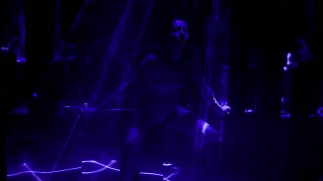 sexual woman in bodysuit posing seductively in dark studio with blue rays, gorgeous female body