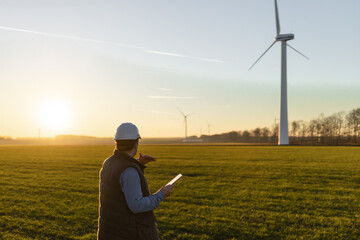 Businessman checking on wind turbine energy production - obrazy, fototapety, plakaty