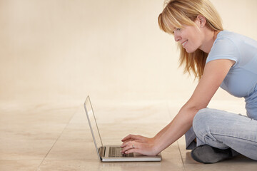 Woman, remote work from home and laptop on floor, smiling and type email for job, copywriter or...