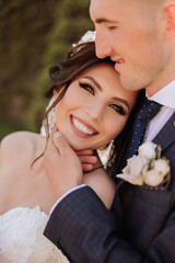 Wedding. Love and couple in garden for wedding. Celebration of ceremony and commitment. Save the date. Trust. The bride and groom embrace. Smile and love. The groom hugs the smiling bride.