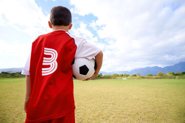Child, back view and soccer player on field for fitness, workout and ready for training on grass. Boy, athlete and ball for exercising and skill development, practice and wellness or sports and match