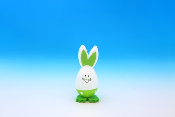 Easter bunny green egg on gradient blue white background. Minimal cute composition with environmentally friendly fun solitary theme.