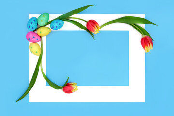 Easter eggs and tulip flowers abstract with white frame on blue background. Minimal floral festive...