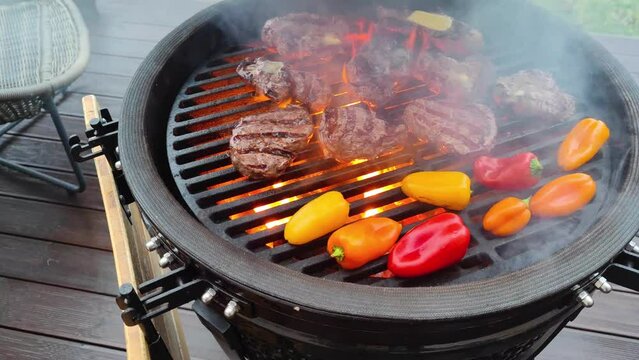 4K footage of kamado egg type barbeque grill standing on a living house terrace with beef sirloin steak, filet mignon and vegetables to be cooked on open fire