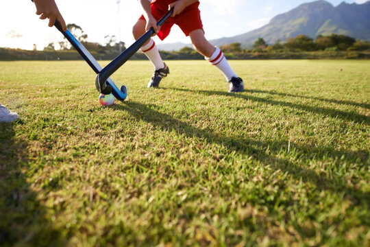 Children, ball and playing hockey on field for game, sports or outdoor match together. Team, kids or players in competition on green grass for tackle, practice or training in fitness or nature