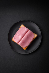 Delicious sandwich with toast bread, ham, tomatoes, salt and spices