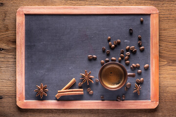 top view glass cup with espresso, coffee beans, star anise and cinnamon sticks on a blackboard with empty space above view - 700973422